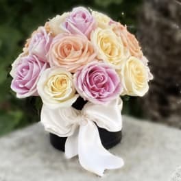 Pastel rose bouquet with a white ribbon on a black box