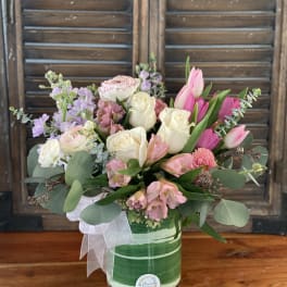 Pink and white mixed flower arrangement in a green striped container