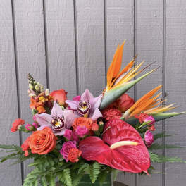 Tropical bouquet with orchids, roses, anthurium, and bird of paradise in a glass vase