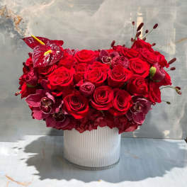 Red rose and orchid arrangement in a ribbed glass vase