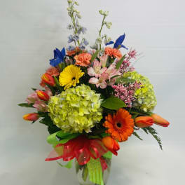 Colorful mixed flower bouquet in a glass vase with ribbon