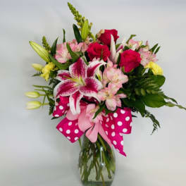 Bouquet of pink and white flowers in a glass vase with a polka-dot ribbon