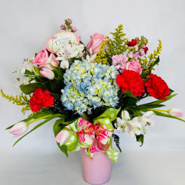 Pink and red mixed bouquet in a pink vase with a ribbon