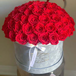 Large bouquet of red roses in a round hat box with a ribbon