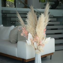 Tall dried floral arrangement in a white vase with beige and pink accents