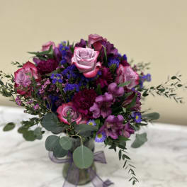 Bouquet of pink and purple flowers in a glass vase with a ribbon