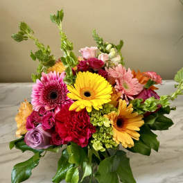 Mixed bouquet of gerbera daisies, roses, and carnations in a glass vase