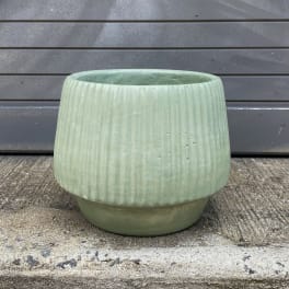 Empty pale green ceramic planter with a ribbed texture
