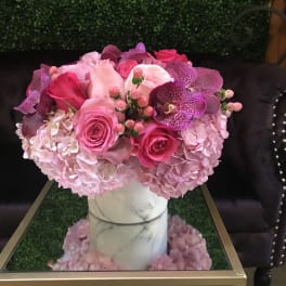 Pink and purple floral arrangement in a white vase
