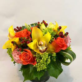 Yellow orchids and orange roses in a low black vase