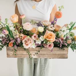 Mixed pastel flowers arranged in a wooden box