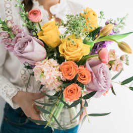 Woman holding a colorful bouquet of roses and tulips in a glass vase