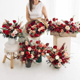 Assorted red and blush rose arrangements with a woman holding a bouquet