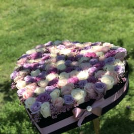 Heart-shaped box filled with pastel roses and small pink flowers