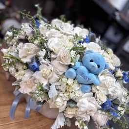 White rose bouquet with a blue teddy bear in the center