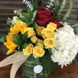 Bouquet of red and yellow roses with white hydrangeas in a glass vase