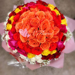 Round bouquet of orange, red, yellow, pink and white roses wrapped in pink paper
