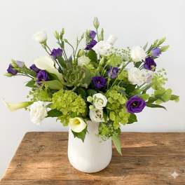 White and purple flowers arranged in a white vase