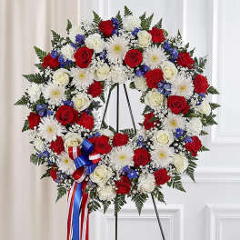 Red, white, and blue floral wreath on a stand with ribbon