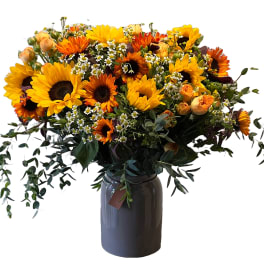 Bouquet of sunflowers and orange blooms in a dark vase