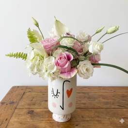 Pink and white roses arranged in a painted ceramic vase