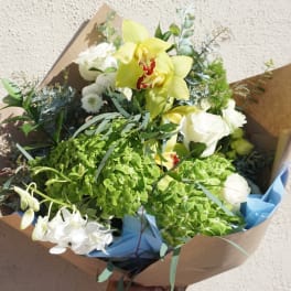Bouquet with yellow orchids, white roses, and green hydrangeas in brown paper