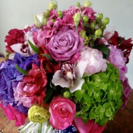 Colorful bouquet with roses, hydrangeas, and orchids in a decorative vase