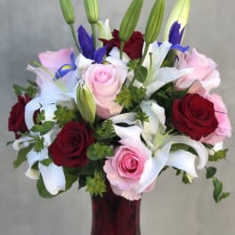 Bouquet of red and pink roses with white lilies in a red vase