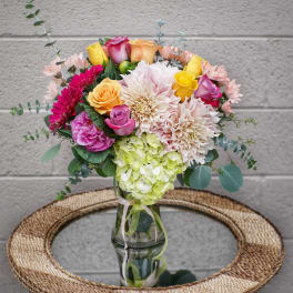 Mixed bouquet of roses, dahlias, and hydrangea in a glass vase