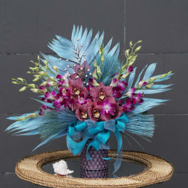 Bouquet of purple orchids and blue feathers in a decorative vase