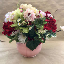 Mixed pink, red, and white flowers arranged in a pink vase