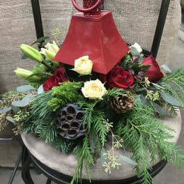 Red lantern centerpiece with roses and lilies on evergreen foliage