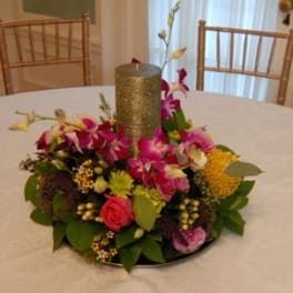 Round floral centerpiece with a gold candle in the middle