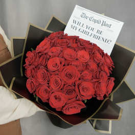 Bouquet of red roses wrapped in black paper with a printed card