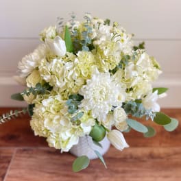 White floral bouquet with hydrangeas, tulips, and eucalyptus in a vase