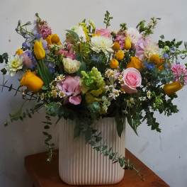 Mixed bouquet in a ribbed white vase with pink, yellow, and white flowers