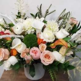 Low floral arrangement with white and blush blooms in a white vase