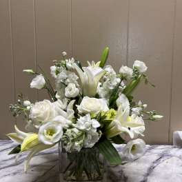 White lilies and roses arranged in a square glass vase