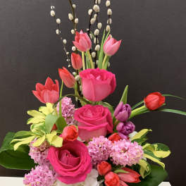 Mixed bouquet of pink roses, tulips, and pussy willow in a white vase