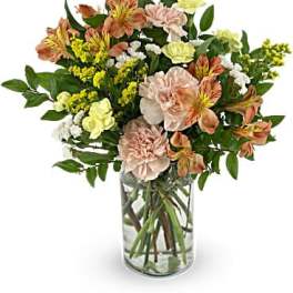 Mixed bouquet of peach and yellow flowers in a clear glass vase