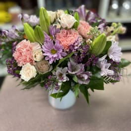 Mixed pink and lavender flowers arranged in a white vase