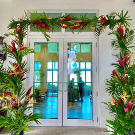 Tropical floral arch with pink and orange flowers framing double doors