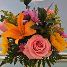 Pink rose and orange lily arrangement in a glass vase