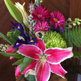 Bouquet with pink lilies, magenta daisies, and purple iris in a vase