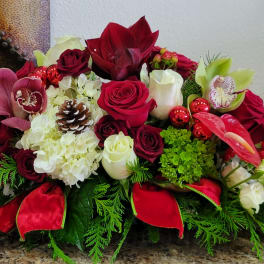 Red and white floral centerpiece with roses, orchids, and pinecones