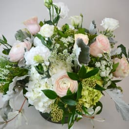 Pastel roses and white blooms arranged in a low vase