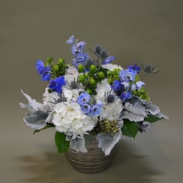 Blue and white floral arrangement in a ribbed metal pot