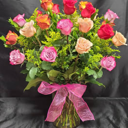 Bouquet of multicolored roses in a glass vase with a pink ribbon
