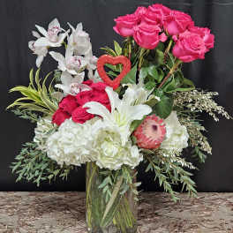 Bouquet of pink roses, white lilies, and orchids in a glass vase