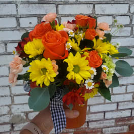 Bouquet of orange roses and yellow daisies in an orange vase